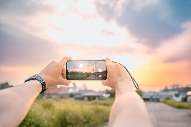 Manzaranın fotoğraflarını çeken bir adam. Cep telefonu kamerası kullanıyor. Öğleden sonra aydınlık ve doğal bir atmosferde..