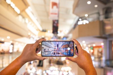 Adam akıllı telefonuyla süpermarketin fotoğrafını çekiyor. Adam cep telefonuyla etrafındaki nesnelerin fotoğrafını çekerken görülüyor. Portre sonuçları çok net ve iyi..
