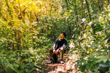 Vahşi doğada dinlenen, doğanın güzelliğine dalmış bir adam. Dokunulmamış Güzellik: Sakin ve Bakir Dağ Ormanı.