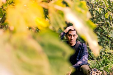 Oturan ve doğrudan kameraya bakan düşünceli adam. Doğayı Kucaklayan Adam: Büyük Açık Havanın Tadını Çıkarmak.