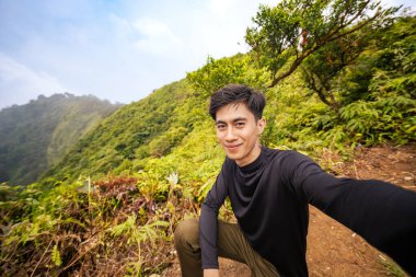 Dağ tırmanışçısı kameraya bakıyor ve nefes kesici bir manzarası var. Sonsuz Ufuk 'la Görkemli Dağ Manzarası.