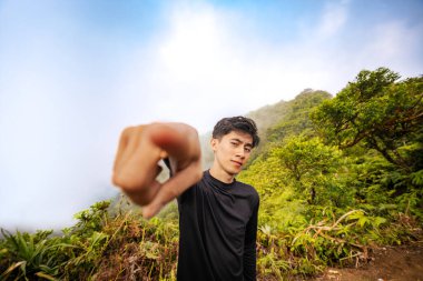 Kendine güvenen genç adam, dostça bir gülümsemeyle kamerayı işaret ediyor. Cesur bilge sizi dağları birlikte fethetmeye davet ediyor..