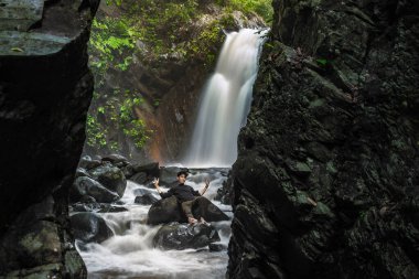 Nehrin ortasında yatan gururlu adam. Şelale, nehir, uçurum ve kaya elementleriyle güzel bir manzara.