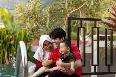 Genç Ebeveynler Oğullarını Tutuyor. Neşeli Bir Aileyle Neşeli anlar.