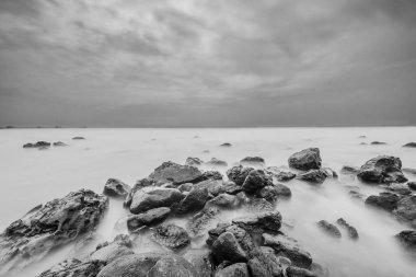 Sahilde kayalıklar oluşmuş. Güzel siyah beyaz plaj manzarası