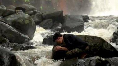 Adam vahşi doğada yüzünü yıkıyor. İnsan vahşi doğada yalnız ve yalnız görünüyor.