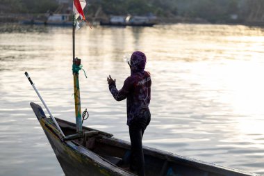 Sunrise 'da tahta teknede duran balıkçı. Endonezya Bayraklı Solo Balıkçı