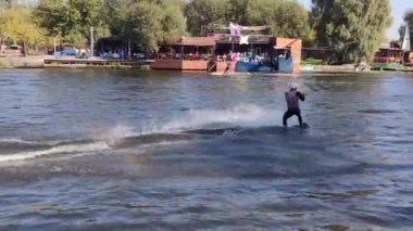 14.09.23 Kyiv Wakeboard çalışanları su hobisi icra ediyorlar. Düşen kişiden gelen su sıçraması ile suya düşüyorlar. Wake Park eğlencesi yaz ekstrem sporları denge sörfünü koruyor.