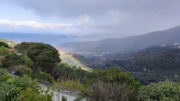 Deniz Dağı Gökkuşağı manzarası Marciana villaları bulutlu bir gün Elba Adası İtalya Yağmurdan sonra Livorno Puslu atmosfer Tropikal dağlık kırsal kasaba tepe manzaralı orman tepe üzerindeki sis bulutu