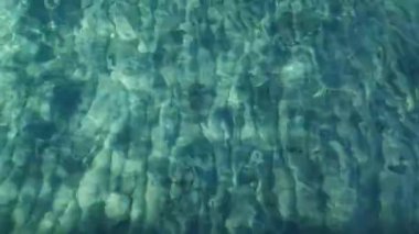 Yazın Yumuşak Mavi Okyanus Dalgası. İtalya 'da şeffaf deniz suyu kumsalı. Yüzey Su Dalgaları Güneş ışınlarıyla aydınlatılıyor. Yüzme havuzunda ışık yansımaları olan mavi bir su..