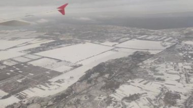 Uçak penceresinden gökyüzü bulutlarına bakıyor. Bulutların üzerindeki kış manzarası. Karla kaplı hava bulutlu. Soğuk mevsim. Kuş bakışı manzara solmuş.