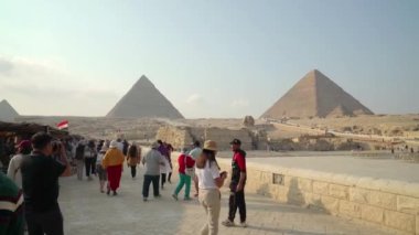 Giza, Mısır. Aralık 2022. Turistler onu takdir etmek için Giza Sfenksine doğru yürüyorlar. Arka planda Giza Piramitleri. Bu piramitler dünyanın yedi harikasından biri olarak kabul edilir..