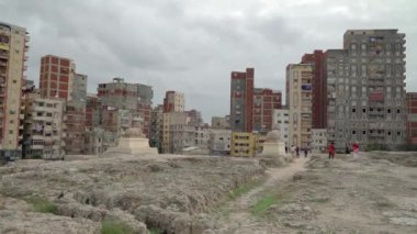İskenderiye, Mısır. Aralık 2022. İskenderiye şehrindeki binalara iki sfenks bakıyor. Serapeum tapınağının kalıntılarında bulunurlar. Bazı turistler fotoğraf çekiyor..