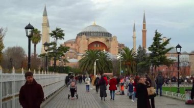 İstanbul, Türkiye. Aralık 2022. Turistler fotoğraf çektirip Sultan Ahmet Parkı 'ndan geçiyorlar. Arka planda Ayasofya Camii 'ni görebilirsiniz..