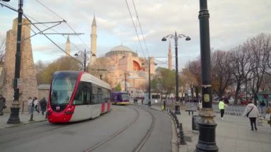 İstanbul, Türkiye. Aralık 2022. İnsanlarla dolu bir elektrikli tren caddeye yaklaşıyor, diğeri uzaklaşıyor, ünlü Ayasofya Camii 'nin önünde..