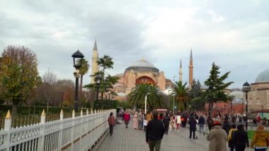 İstanbul, Türkiye. Aralık 2022. Dolly içeride. Turistler fotoğraf çektirip Sultan Ahmet Parkı 'ndan geçiyorlar. Arka planda Ayasofya Camii 'ni görebilirsiniz..