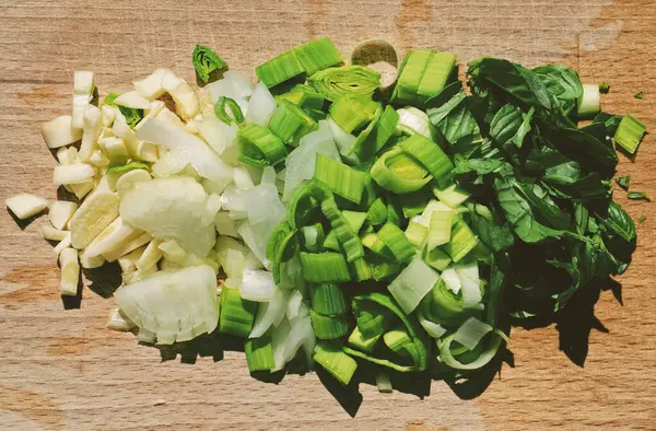 Green vegetables - white green transition - garlic, onion, leek, basil - cutting on a wooden plate