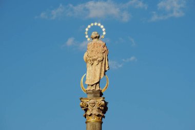 Arka planda açık mavi gökyüzü olan bir sütuna Aziz Peter heykelinin detaylı fotoğrafı