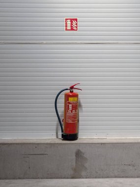 Depodaki duvarda yangın söndürücü var. Fabrikanın güvenlik önlemi.