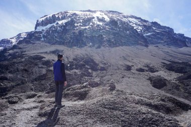 Karlı zirvenin önündeki Avrupalı yürüyüşçü Kilimanjaro Dağı - amaçlarınıza ulaşın - hayalperest - motivasyon - kayalık arazi