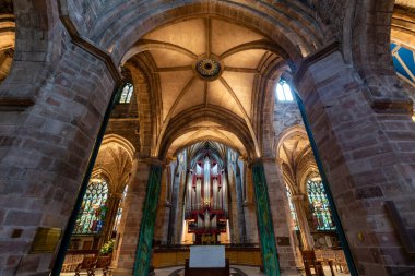 Edinburgh, İskoçya - 20 Kasım 2017: Edinburgh Katedrali 'nin görkemli iç mekanı, uzun taş sütunlar, karmaşık kurdeleli kasalar ve büyük süslü cam pencerelerle çevrili çarpıcı Gotik tarzı sunak alanı. Büyük boru orgu reklamı.