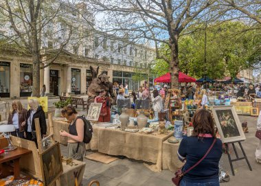 Cheltenham, İngiltere - 12 Nisan 2025: Cheltenham 'da canlı bir açık hava pazarı açılır, arka planda Waterstone' lar görünür, bir bahar günü birçok ziyaretçi çeker.
