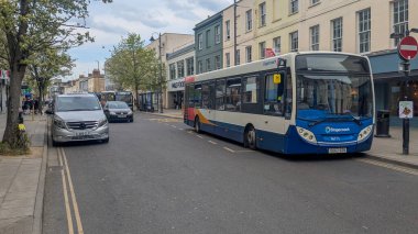 Cheltenham, İngiltere - 12 Nisan 2025: Bir Posta Arabası Enviro200 otobüsü bulutlu bir günde Cheltenham, İngiltere 'de bir sokakta bekliyor.