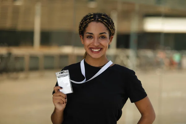 Smiling woman holding an identification card outdoors