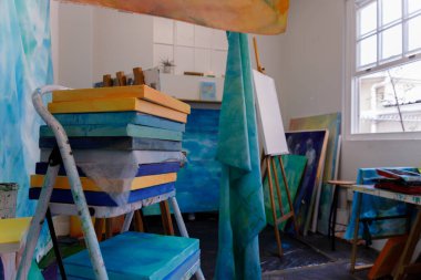 Sanat eserleri sanatçılar stüdyosunda bir tabureye yığılmış.