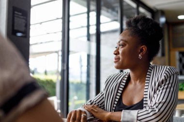 Cheerful african american young female professional laughing and looking away while working in modern corporate office