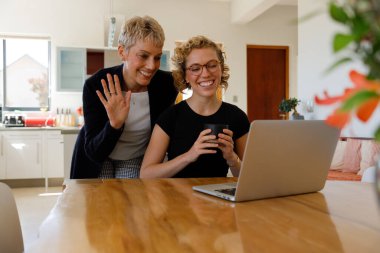 Mature mother and daughter making a video call on their laptop at home. Smiling mother and daughter calling family on laptop.