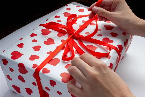女性の手を心を閉じてギフトボックスのリボンをほどく バレンタインデー クリスマス その他の休日のコンセプト — ストック写真