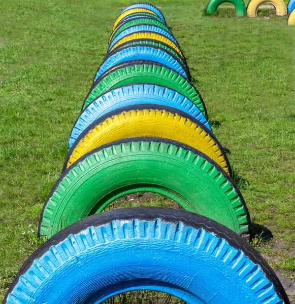 緑の芝生の上でカラフルなゴムタイヤ 子供の運動場 公園の遊び場のためのゴムホイールを使用します 車輪の再利用 — ストック写真