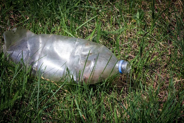 stock image Thrown a plastic bottle on the grass. The concept of environmental pollution with garbage and household waste disposal.