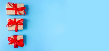 Mavi arka planda kırmızı fiyonklu hediye kutuları. Pankart. Uzayı kopyala Düz yatıyordu. Üst Manzara. Herhangi bir tatil konsepti.