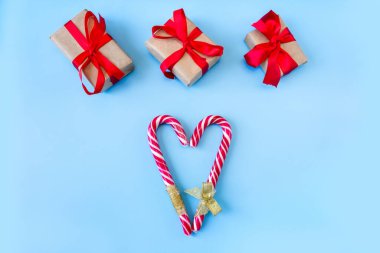 Mavi arka planda kalp şeklinde karamel çubuklu hediye kutuları. Kartpostal Noel ve Yeni Yıl kavramı.