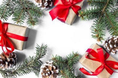 Noel süslemelerinin çerçevesi kırmızı yaylı hediye kutuları, çam kozalakları ve beyaz arka planda ladin dalları. Kartpostal Uzayı kopyala Düz yatıyordu. Üst görünüm.