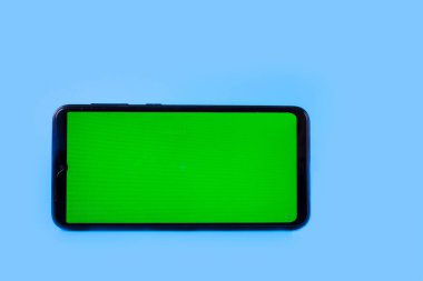 Mavi arka planda yeşil ekranlı yatay pozisyonda akıllı telefon. Krom anahtar. Model.