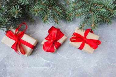 Beton arka planda ladin dalları olan şenlikli hediye kutuları. Yeni yıl ve Noel kavramı. Flatlay. Kopyalama. Kartpostal.