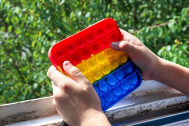 Çocukların elleri pencerede stres önleyici bir popit tutuyor..