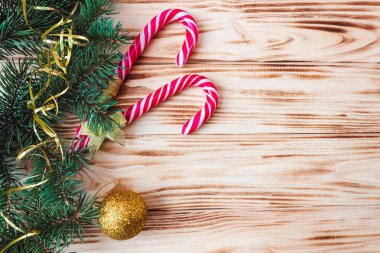 Tahta bir arka planda karamel çubukları, oyuncak ve köknar dalları. Uzayı kopyala Noel ve Yeni Yıl konsepti. Kartpostal Düz yatıyordu.