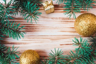 Ahşap bir arka planda yılbaşı ve yeni yıl modeli. Çerçeve, köknar dalları ve oyuncaklardan yapılmıştır. Yukarıdan bak. Düz yatıyordu. Boşluğu kopyala.