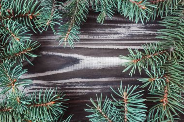 Ahşap bir arka planda köknar dallarından yapılmış bir çerçeve. Kartpostal Uzayı kopyala Düz yatıyordu. Yukarıdan görüntüle.