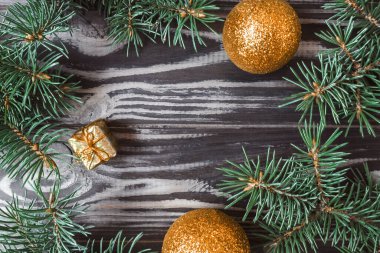 Ahşap bir arka planda yılbaşı ve yeni yıl modeli. Çerçeve, köknar dalları ve oyuncaklardan yapılmıştır. Yukarıdan bak. Düz yatıyordu. Boşluğu kopyala.