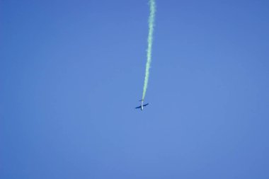 Mavi gökyüzünde duman izi olan bir uçak. Hava gösterisi.