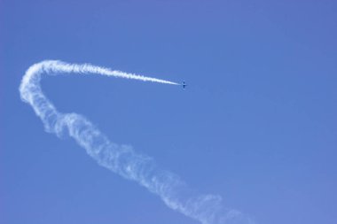 Mavi gökyüzünde duman izi olan bir uçak. Hava gösterisi.