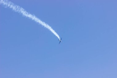 Mavi gökyüzünde duman izi olan bir uçak. Hava gösterisi.