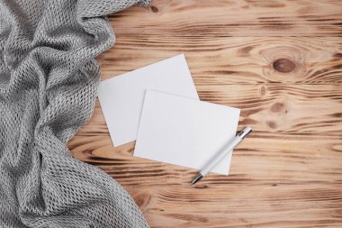 Aydınlık bir tahta zemin üzerinde kumaş ve kalemle boş bir sayfa oluşturun. Tasarım için kağıt şablonu. Kartvizit. Düz yat, boşluğu kopyala.