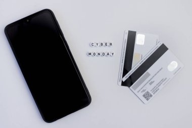 Beyaz arka planda akıllı telefon ve ödeme kartı olan siber pazartesi mektupları. Çevrimiçi alışveriş kavramı.