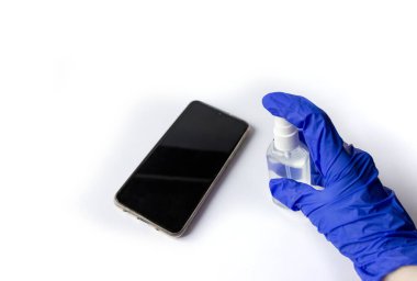 Akıllı telefon antiseptiğinin dezenfeksiyonu. Eldivendeki antibakteriyel, beyaz arka planda izole bir şekilde telefonu temizliyor. Temizlik ve hijyen kavramı.